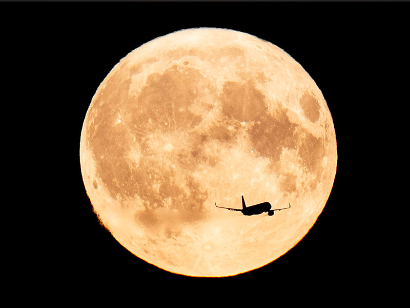 This photo shows a plane flying over the Super Blue Moon as seen from Kastellet in Copenhagen on August 19, 2024. — AFP