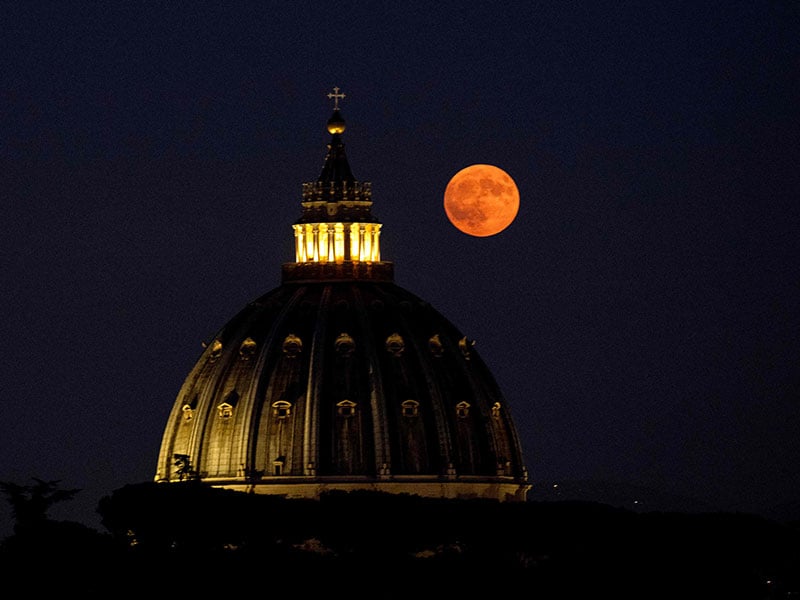 This photograph taken in Rome shows the Super Blue Moon rising over the dome of St Peter´s Basilica in the Vatican City, on August 19, 2024. — AFP