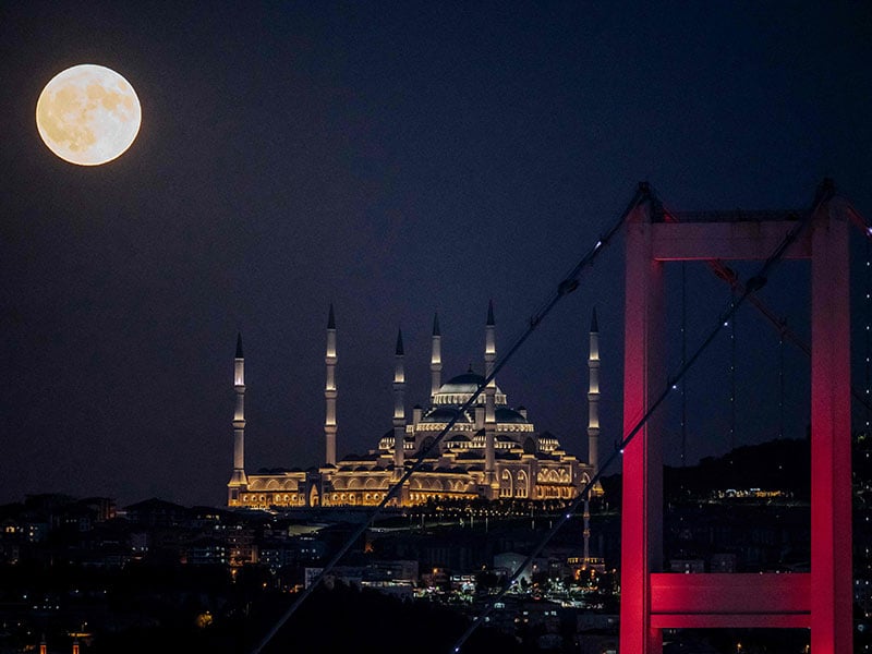 A super blue moon rises behind the 15 July Martyrs' Bridge and the Camlāca Mosque in Istanbul on August 19, 2024. — AFP