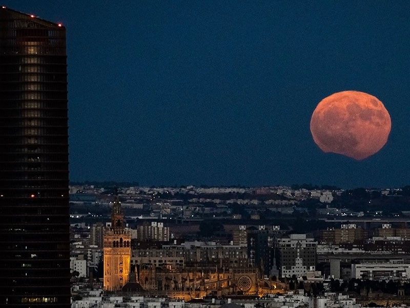 The image shows the Pelli Tower and the cathedral as the full moon rises over Seville on August 19, 2024. — AFP