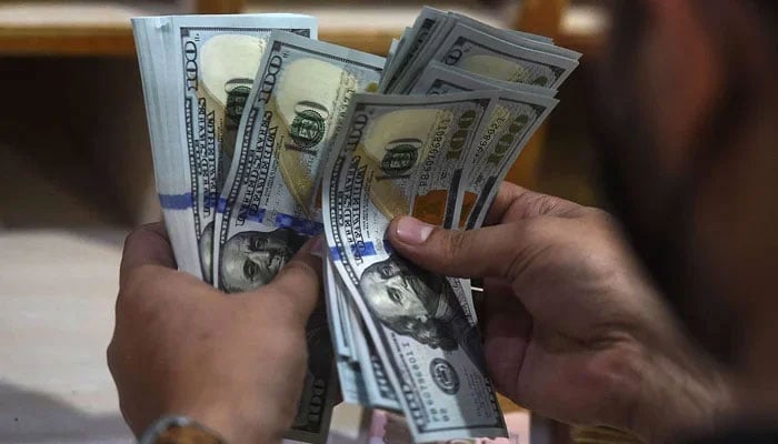 A currency exchange dealer counting $100 bills. — AFP/File