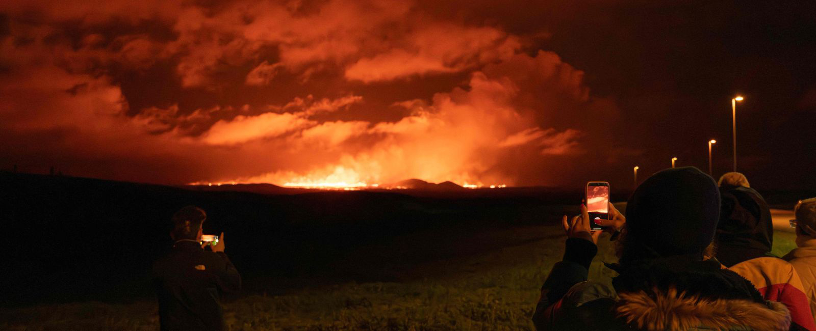 People taking pictures of lava and smoke erupting from a volcano near Grindavik on the Icelandic peninsula of Reykjanes on August 22, 2024. — AFP