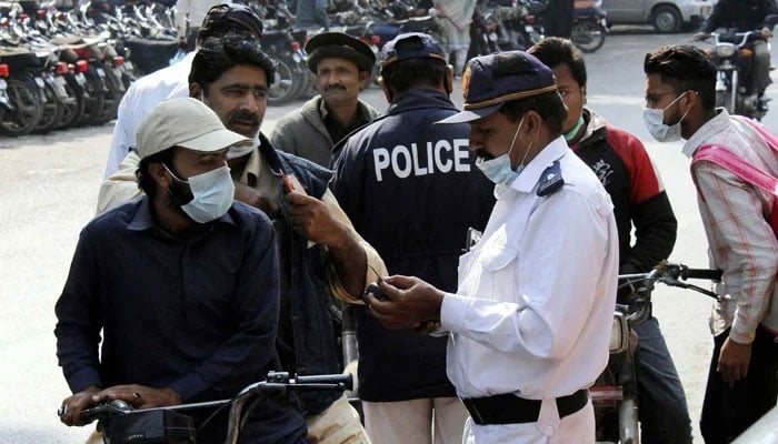 Traffic police staff issuing challan to people for violating traffic rules at Zainab Market in Karachi February 04, 2021. — PPI/File