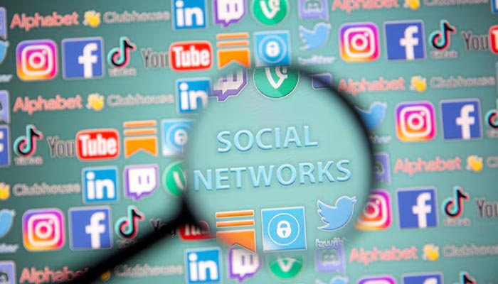 In this illustration taken on May 25, 2021, the words Social Network and social media logos are seen through a magnifying glass. — Reuters