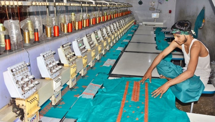 A worker is busy in preparing the design on the fabric with the help of machine at a local textile factory in Hyderabad on May 2, 2024. —APP