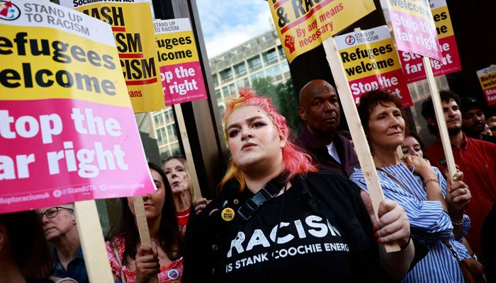 People hold anti-racism placards as they take part in a Stop the Far-right demonstration on a National Day of Protest, outside of the headquarters of the Reform UK political party, in London on August 10, 2024. — AFP