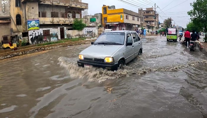 A vehicle passing through rain water accumulated on road in Karachi on August 18, 2024. —INP