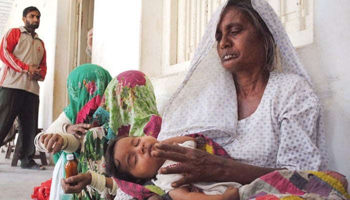 A mother holds a baby on her lap while sitting on a floor in a Pakistani city. — AFP/File