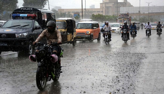 Commuters pass through a road during heavy downpour of monsoon season, at Sharea Faisal road in Karachi on July 9, 2024. — PPI