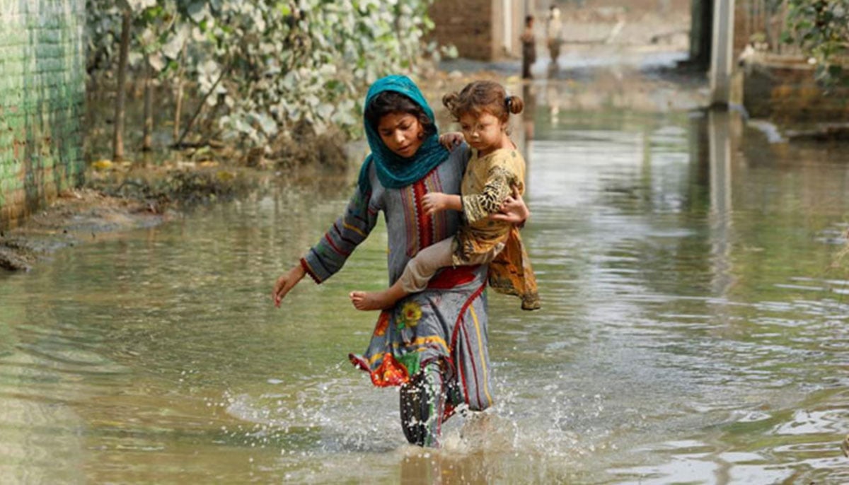 A girl carries her sibling as she walks through stranded flood water, following rains and floods during the monsoon season in Nowshera, September 4, 2022. — Reuters