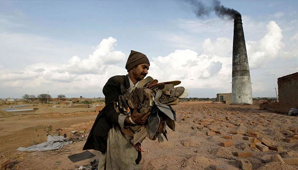 A worker carries shoes to be burned in the kiln of a brick factory in Islamabad, March 9, 2017. — Reuters