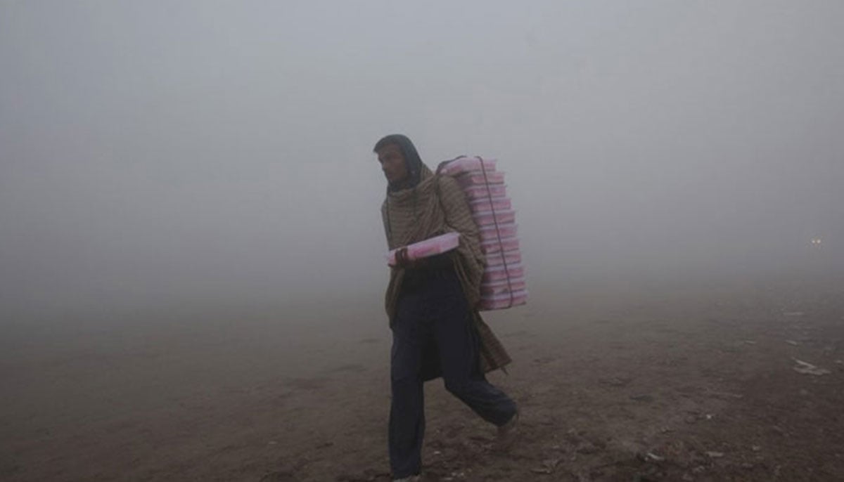 A vendor carries plastic boxes on a smoggy morning in Lahore, January 3, 2019. — Reuters