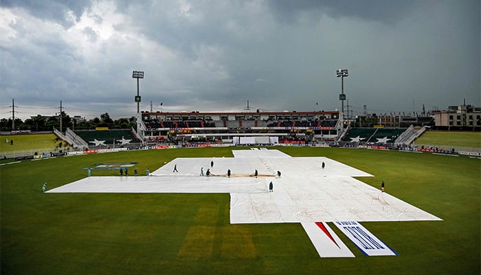 Groundmen cover the pitch owing to dark clouds as poor light halts play during the fourth day of the second and last Test cricket match between Pakistan and Bangladesh at the Rawalpindi Cricket Stadium in Rawalpindi on September 2, 2024. — AFP