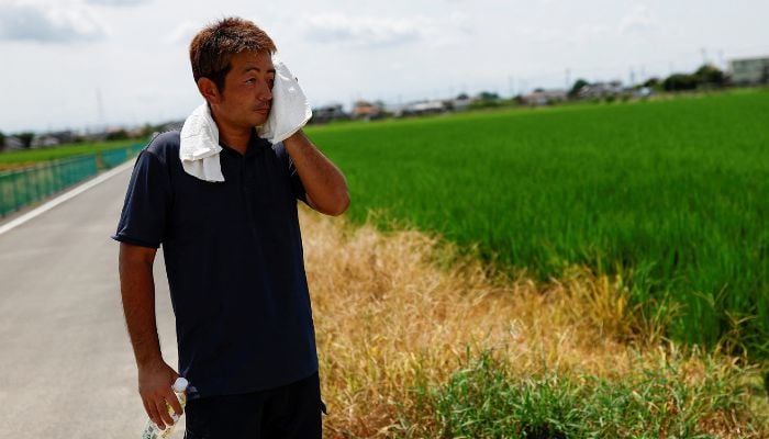 Yukihiro Kurosawa, a 39-year-old farmer, wipes his sweat during a hot summer day, near his fields in Meiwa, Gunma prefecture, Japan on August 7, 2024. — Reuters