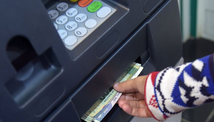 A person withdrawing cash from an Automated Teller Machine (ATM). — AFP/File