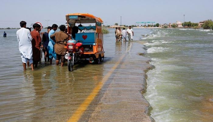 Displaced people stand on flooded highway, following rains and floods during the monsoon season in Sehwan, Pakistan, September 16, 2022. — Reuters