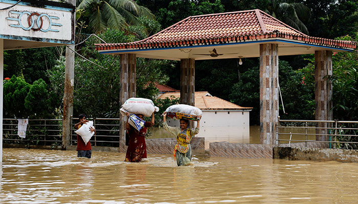 People carrying sacks, wade through flood water, amid severe flooding in the Fazilpur area of Feni, Bangladesh, August 26, 2024. — Reuters