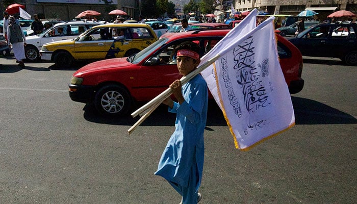 An Afghan boy carrying flags walks on a street during a rally by the Taliban to mark the third anniversary of the fall of Kabul, in Kabul, Afghanistan, August 14, 2024. — Reuters