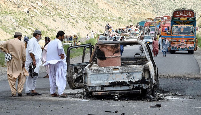 People look at a charred vehicle near a collapsed railway bridge a day after a blast by militants at Kolpur in Bolan district, Balochistan province on August 27, 2024. — AFP