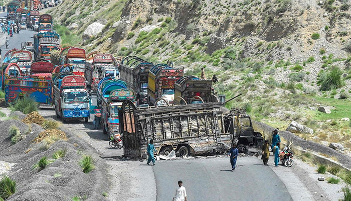 People look at a charred vehicle near a collapsed railway bridge a day after a blast by militants at Kolpur in Bolan district, Balochistan on August 27, 2024. — AFP