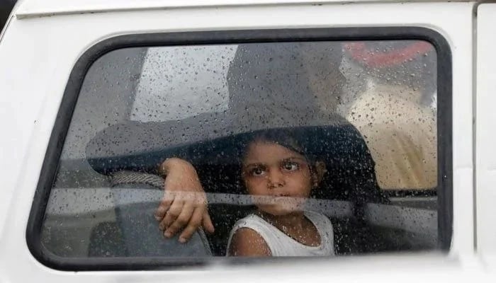 A girl looks out of a car window with raindrops during the seasons first monsoon rain in Karachi on July 6. 2020. — Reuters