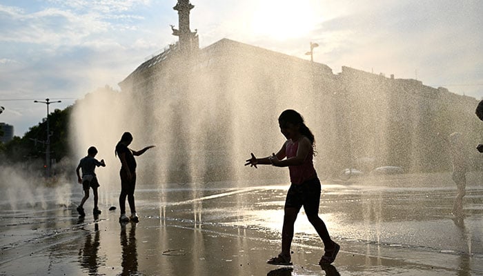 Children play under a water sprinkler during a heat wave in Vienna, Austria, August 14, 2024. — Reuters