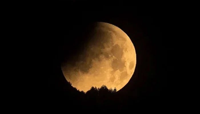 A  lunar eclipse occurring as a shadow falls on the moon seen through a telescope. — AFP/File