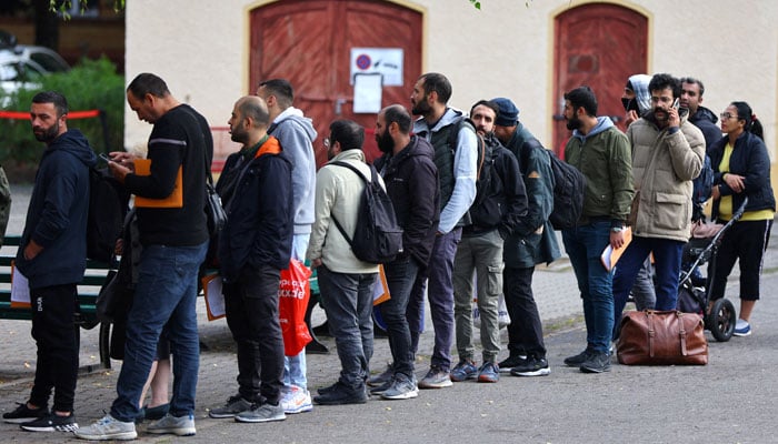 Migrants queue in a waiting area to be escorted to a registration office at the arrival centre for asylum seekers in Reinickendorf district, Berlin, Germany, October 6, 2023. — Reuters