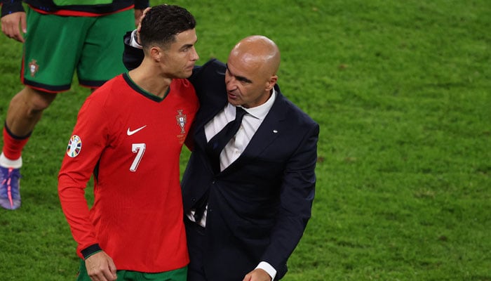 Portugals Cristiano Ronaldo and head coach Roberto Martinez react at the end of the UEFA Euro 2024 quarter-final football match against France at the Volksparkstadion in Hamburg on July 5, 2024. — AFP