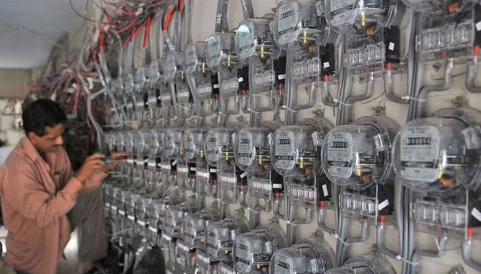 A technician fixes new electricity meters at a residential building in Pakistan, in this undated photo. — AFP/File