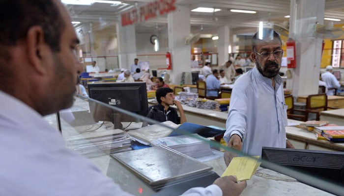 A Pakistani Post office employee takes mail from a customer in Islamabad. — AFP/File