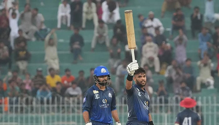 Usman Khan raises his bat after scoring century. - PCB