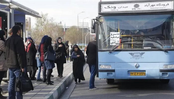 Iranians stand at a bus stop on a main road in the Islamic republics capital Tehran. — AFP/File