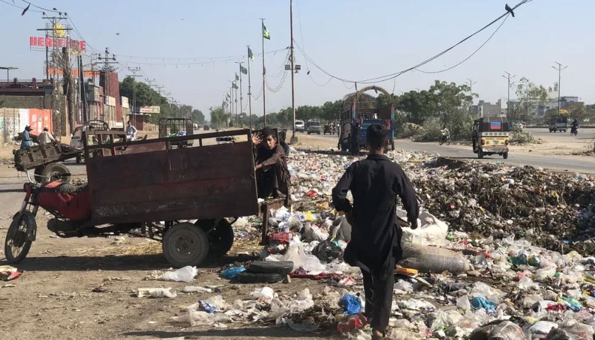 A minor waste picker sits next to a roadside garbage heap near Al-Asif Square, Karachi on November 11, 2023. — Reuters