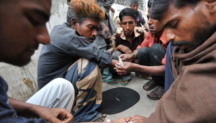 This picture taken on March 26, 2009 shows Pakistani addicts injecting heroin into each other on the roadside in Karachi. — AFP