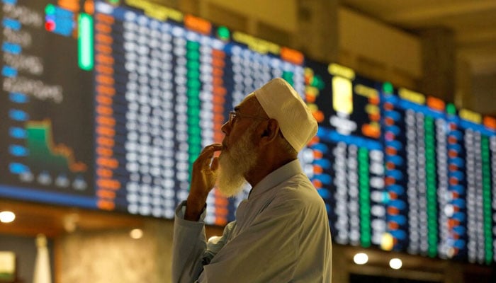 A stock broker reacts while monitoring the market on the electronic board displaying share prices during trading session at the Pakistan Stock Exchange, in Karachi, July 3, 2023. — Reuters