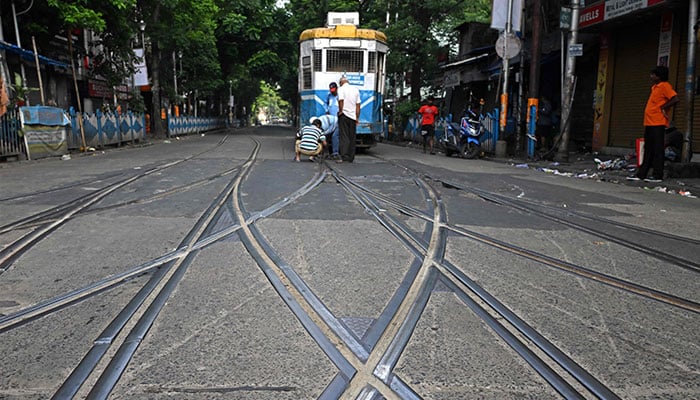 Tram workers manually change the lane on a street in Kolkata on September 18, 2024. — AFP