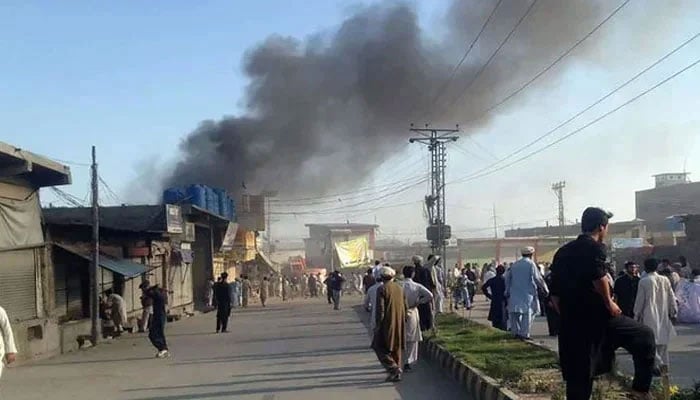 Residents gather on a road as smoke billows after a blast at a market in Parachinar, capital of Kurram district. — AFP/File