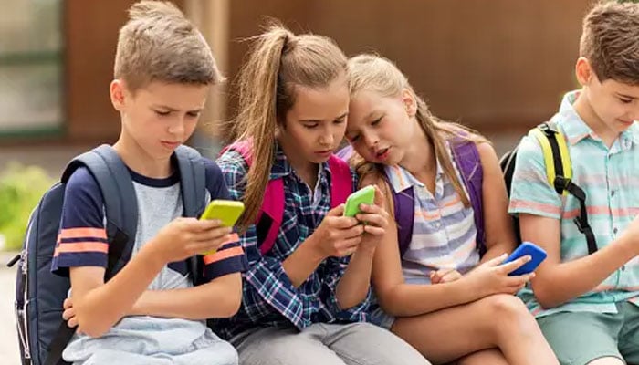 A representational image showing a group of school children using smartphones. — Unsplash