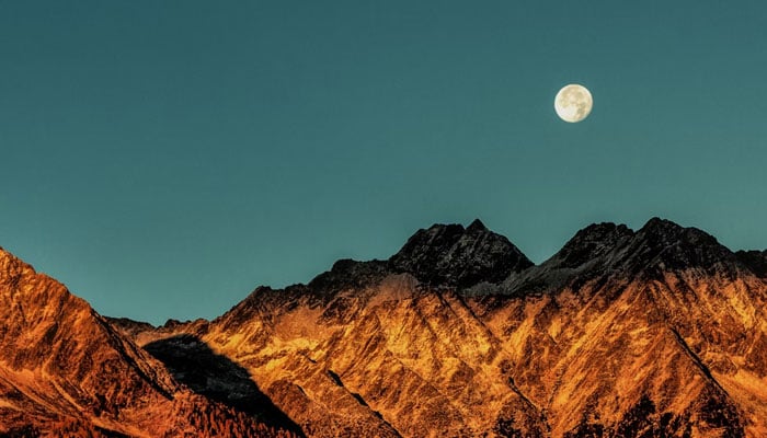 A representational image showing the moon over mountains. — Unsplash