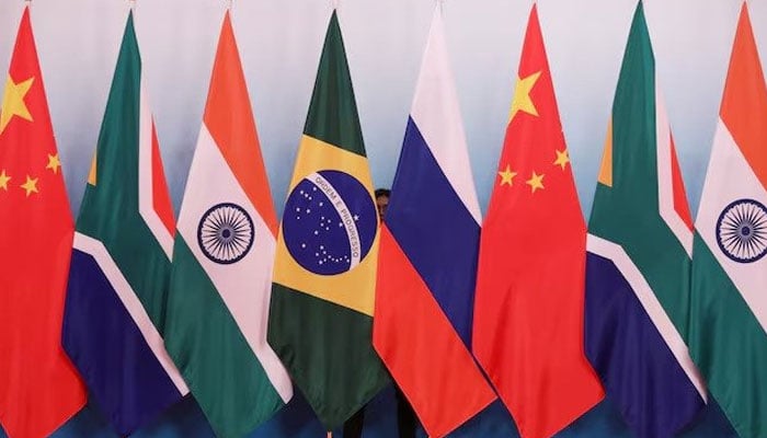 A staff worker stands behind the national flags of Brazil, Russia, China, South Africa and India to tidy the flags before a group photo during the BRICS Summit at the Exhibition Center in Xiamen, China, September 4, 2017. — Reuters