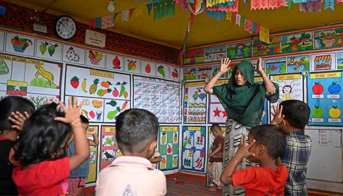 A Rohingya woman teaches at a school in a refugee camp in Ukhia on September 12, 2024. — AFP