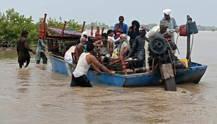 People with their belongings wade through the flood affected area of Chanda Singh Wala village in Kasur district on August 22, 2023. — AFP