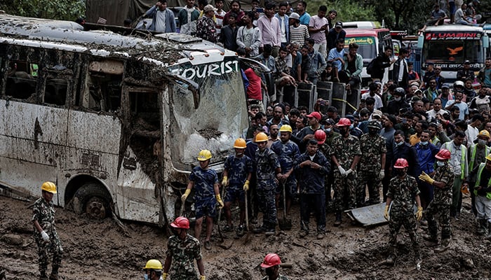 People stranded at the Tribhuwan Highway look on as rescue personnel work to retrieve the bodies of the victims from a landslide triggered by heavy rainfall in Dhading, Nepal on September 29, 2024. — Reuters