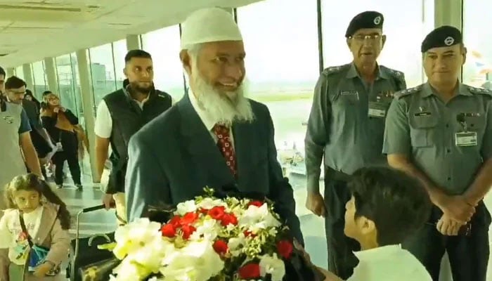 Islamic scholar and public speaker Dr Zaik Naik is greeted with a bouquet of flowers upon his arrival at the Islamabad airport on September 30, 2024. — Screengrab via X/@asadnasir2000