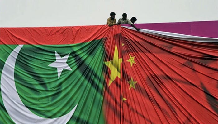 Workers adjust a poster featuring flags of Pakistan and China in this undated image. — AFP/File