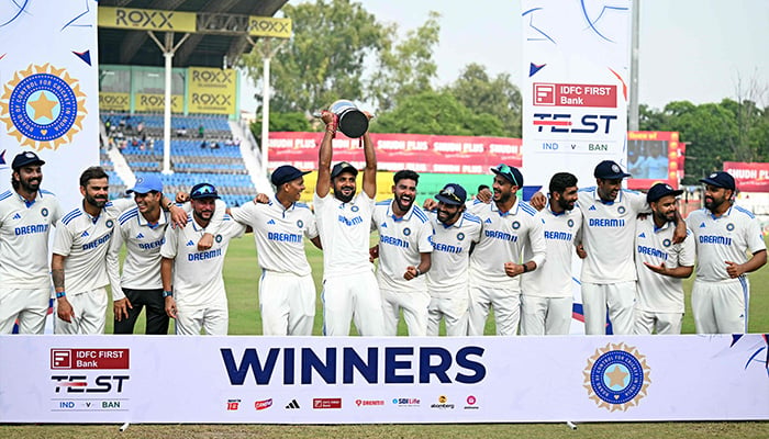 Indias players celebrate with their trophy at the end of the second Test cricket match between India and Bangladesh at the Green Park Cricket Stadium in Kanpur on October 1, 2024. — AFP