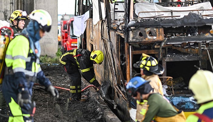 A firefighter sprays water on a burnt-out bus that was carrying students and teachers on the outskirts of Bangkok, Thailand, on October 1, 2024. — AFP