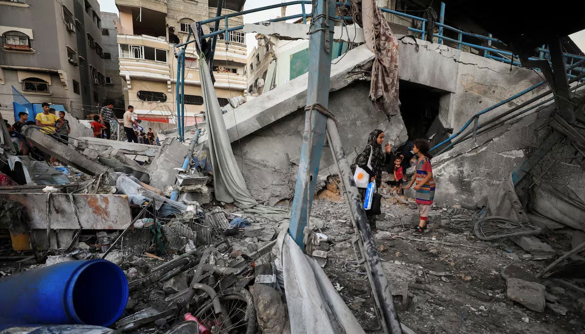 Palestinians stand amid debris at a UN-run school sheltering displaced people in Gaza City in July. — Reuters/File