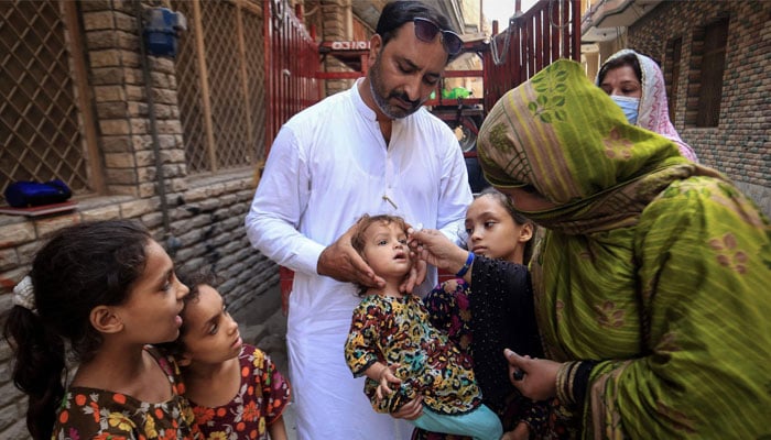 A health worker administers polio drops to a child during a door-to-door vaccination campaign in Peshawar on September 12, 2024. — AFP